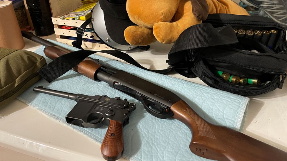 Weapons lie beside a big stuffed toy on a family's window ledge