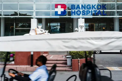 Getty Images A man drives a vehicle in front of the Bangkok Hospital