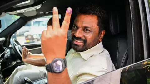 Getty Images Sri Lankan President Anura Kumara Dissanayake shows his inked finger as he leaves a polling station after casting his ballot to vote in Sri Lanka's parliamentary election in Colombo on November 14, 2024.