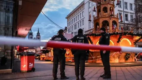 EPA Three German police officer stand behind red and white police tape by the Christmas markets