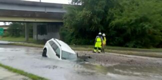 Woman rescued after car plunges into flooded sinkhole